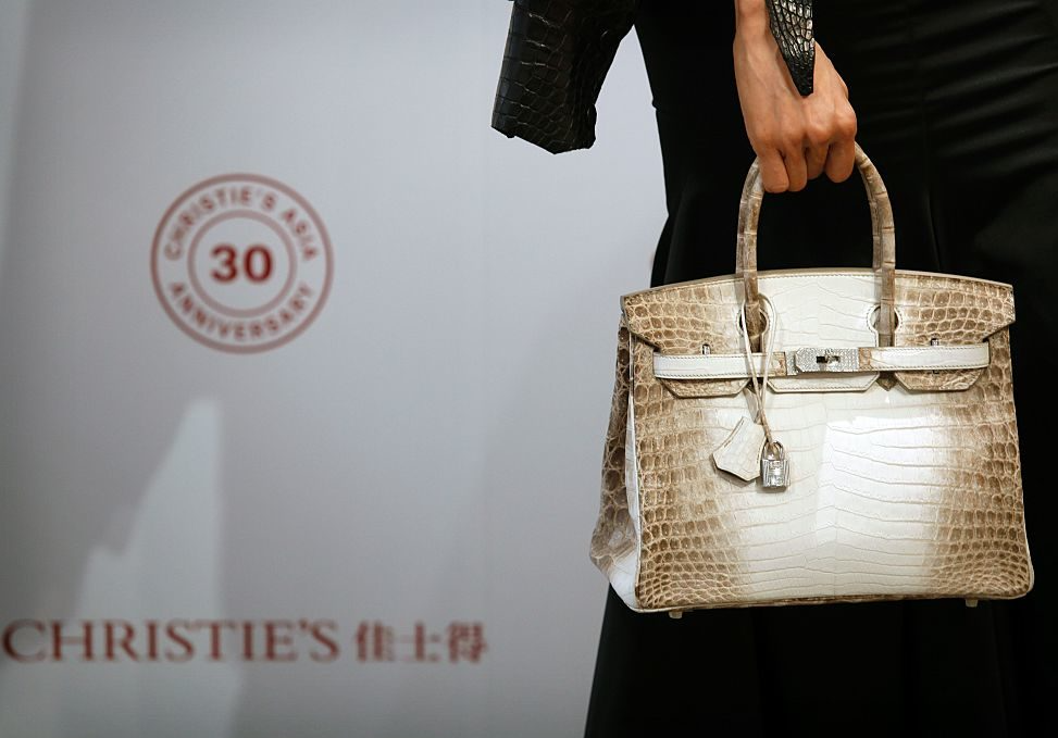 Woman holds crocodile skin Hermès Birkin handbag